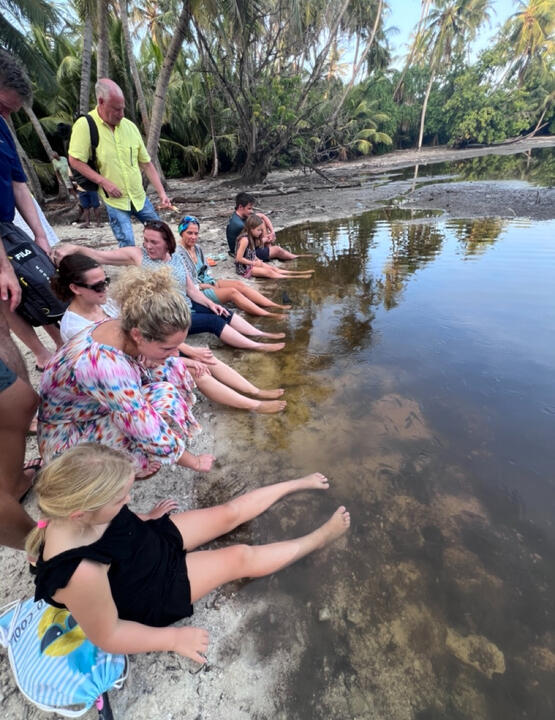 Reisegruppe sitzt mit den Füßen im Wasser einer abgelegenen Lagune im Dschungel