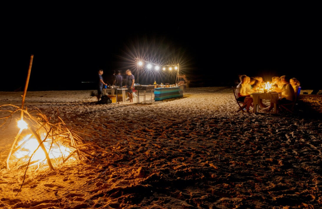 Lagerfeuer und gedeckter Tisch am Strand bei Nacht, weit entfernt von jeder Straße