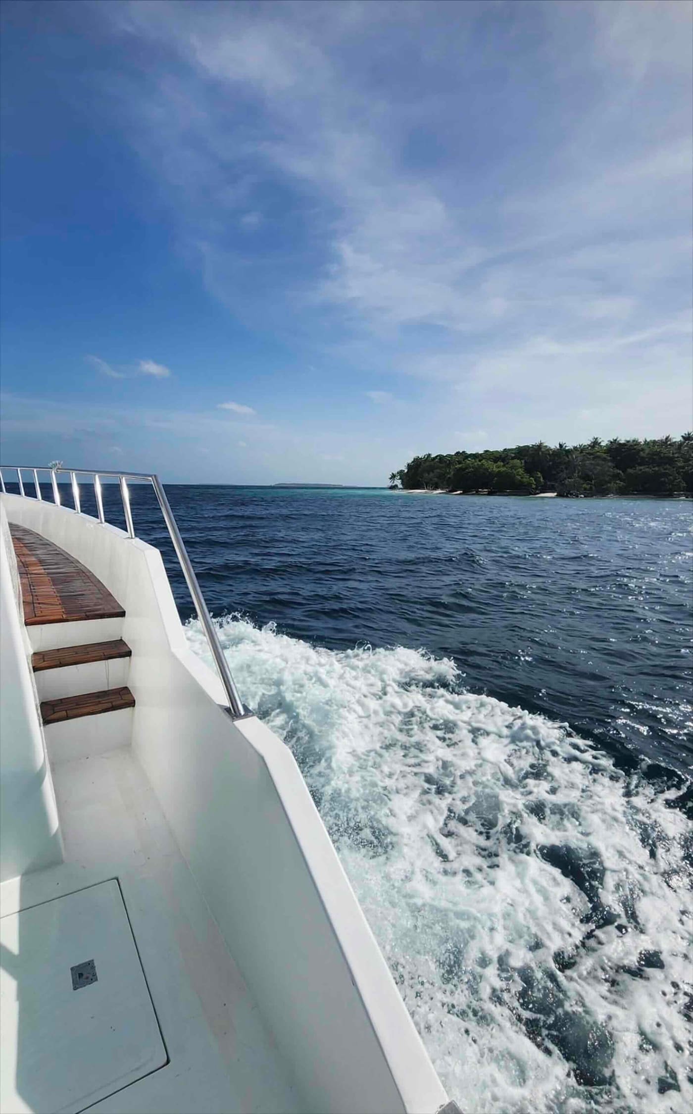 Blick vom Achterdeck auf das Kielwasser und eine Insel