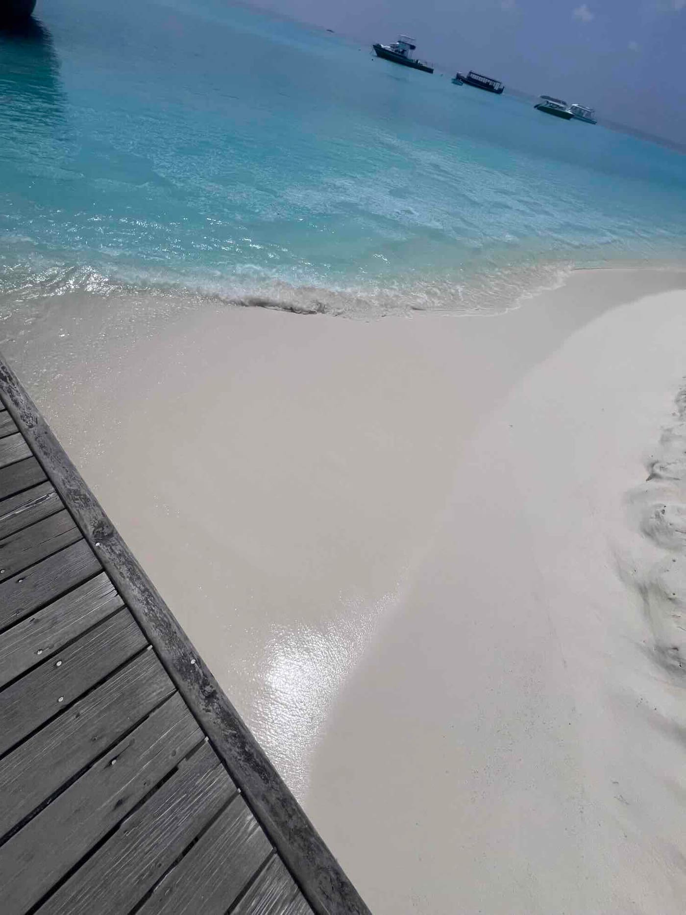 Blick von einem Steg auf eine Sandbank und türkises Wasser