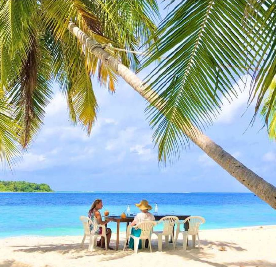 Gemeinsames Essen an einem Strandtisch unter einer Palme